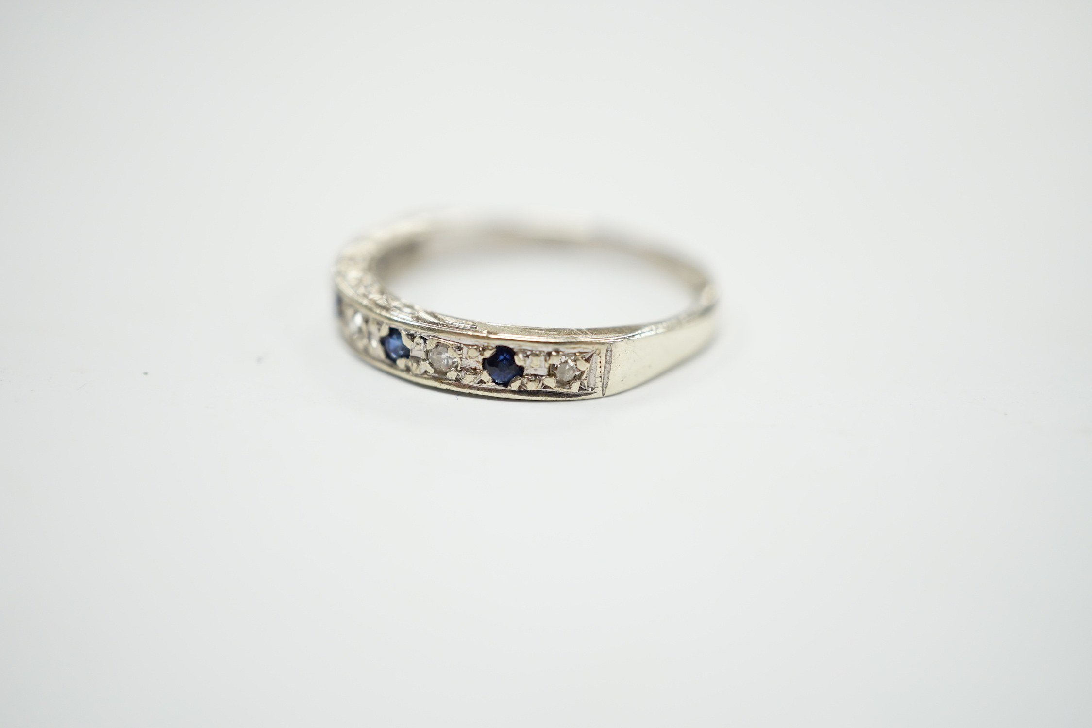 A modern 9ct white hold sapphire and diamond chip set half hoop ring, size N, gross weight 2.1 grams.